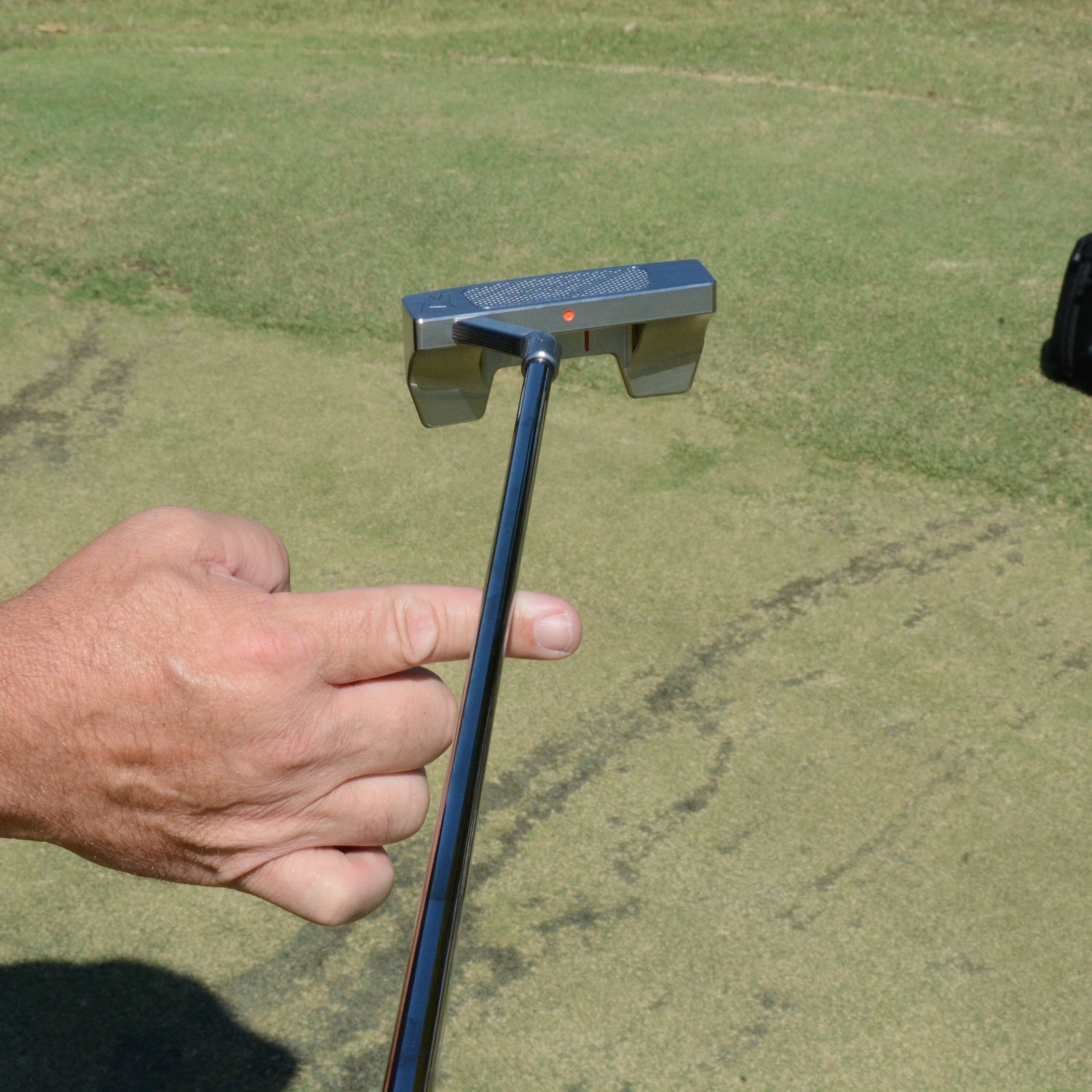 Rhyno Putter balancing on a finger with it's face pointing up.